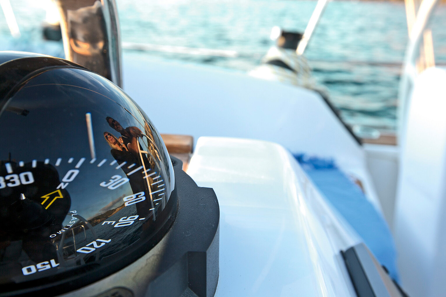Schwarzer Kompass auf der Steuerkonsole einer Yacht mit Blick auf das offene Wasser